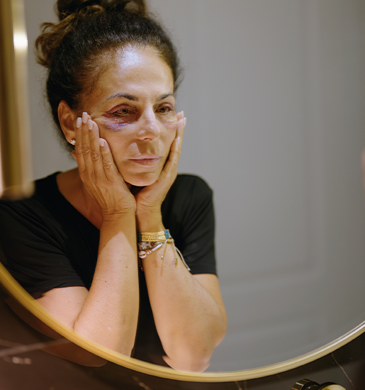 Middle age hispanic woman suffering for domestic violence looking on mirror bruise on eyes at bathroom