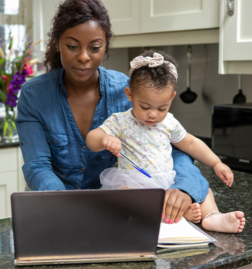 Woman working on laptop at home and taking care of baby daughter