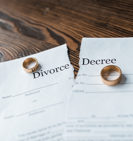 close up shot of teared divorce decree and engagement rings on wooden surface