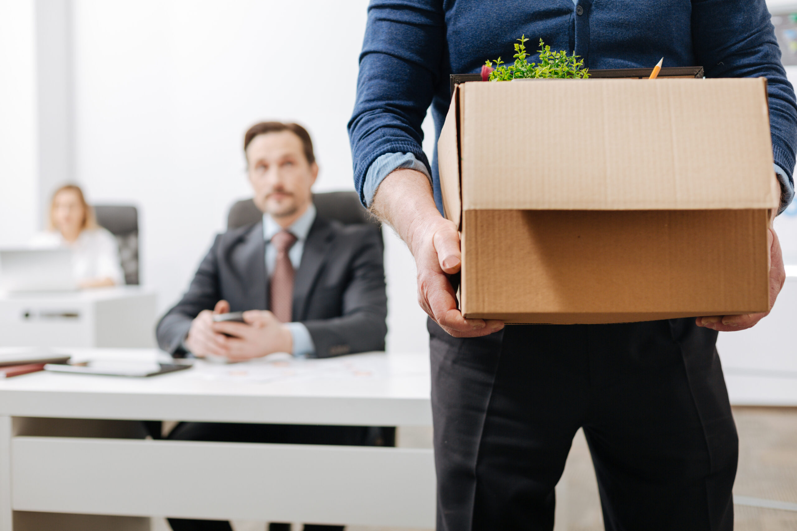 Beginning of the new life. Concentrated involved aged employee standing and holding the box with his belongings while leaving the office