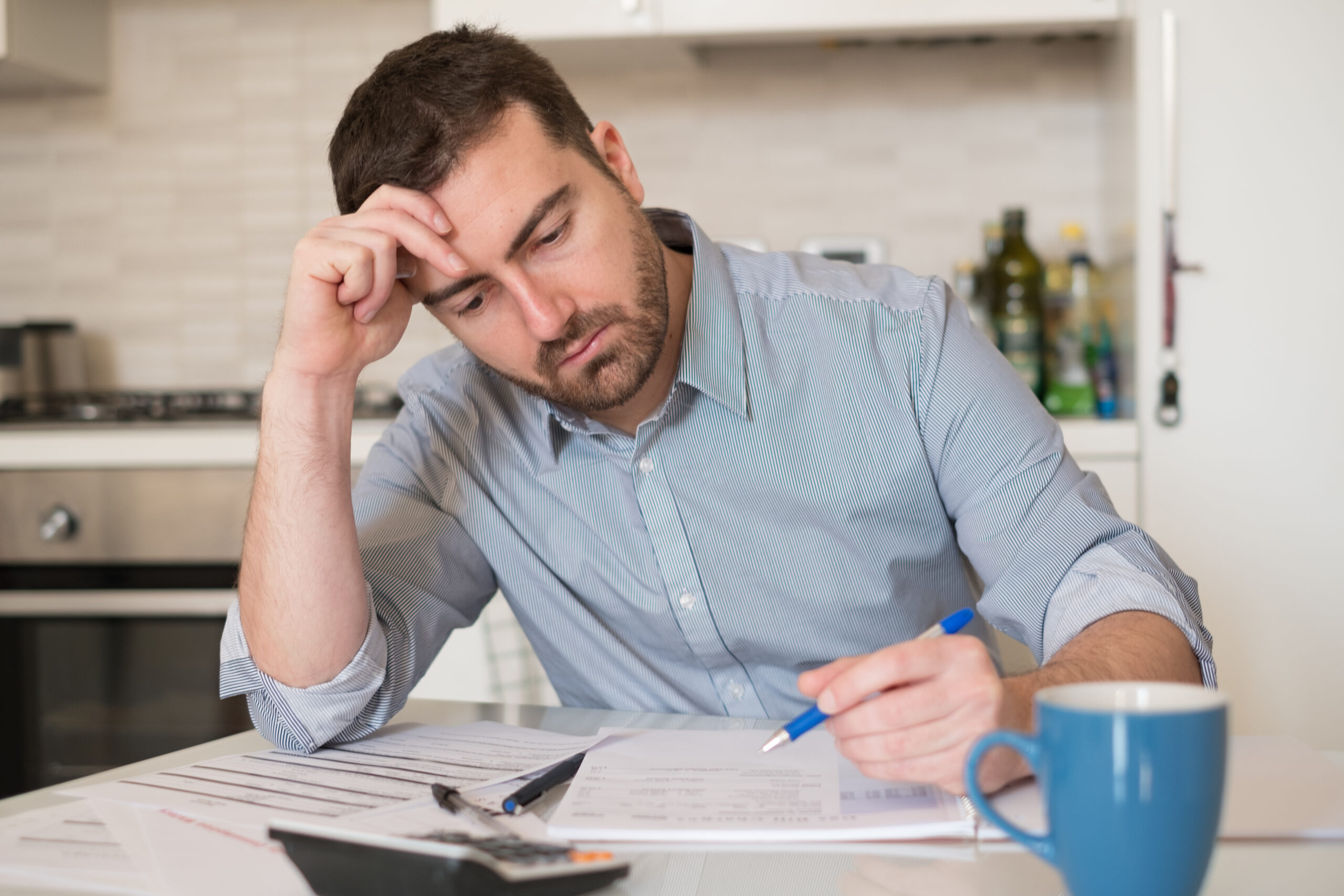 Frustrated man calculating bills and tax expenses